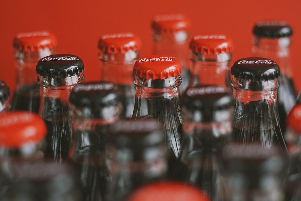 Sealed Coca-Cola bottles with red and black caps, illustrative photo.
