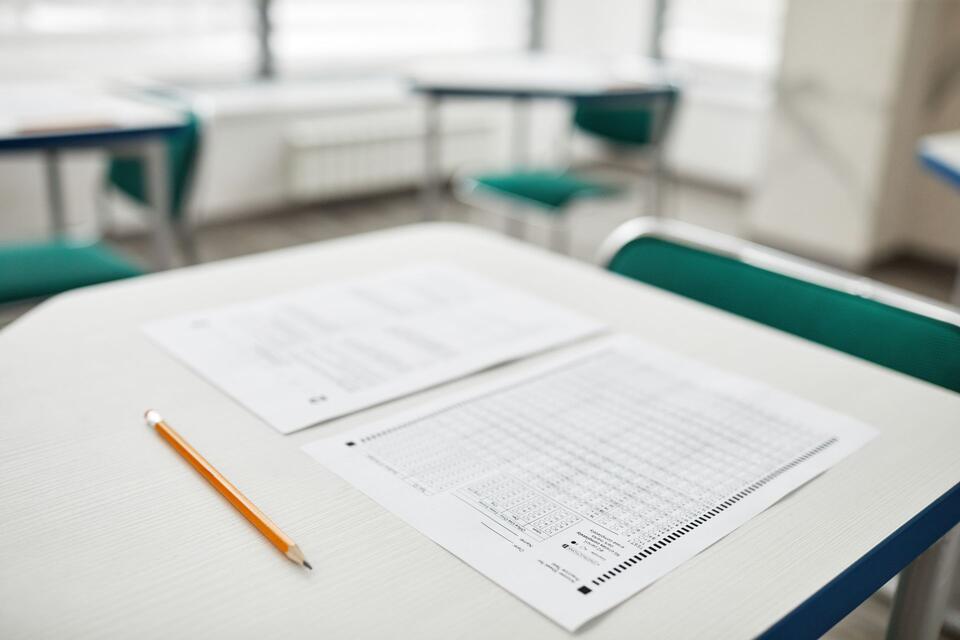 Des feuilles d’examen et un crayon posés sur une table de classe vide, photo d’illustration.