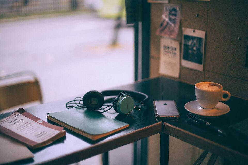 Un casque, un smartphone, des carnets et un café sur une table, photo d’illustration.