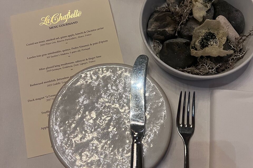 A printed menu and plates on a restaurant table.