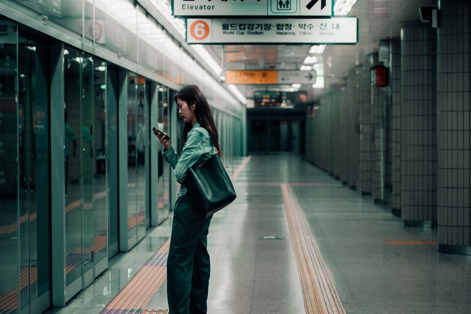 Een reizigster bekijkt haar telefoon op een metroperron in Seoul, illustratieve foto.