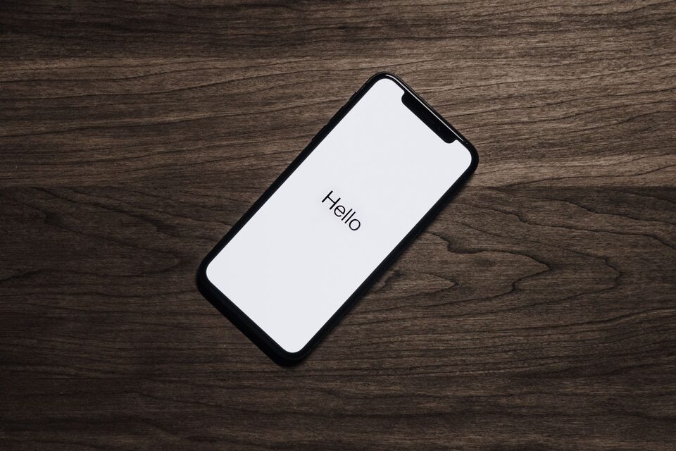 Un iPhone affiche « Hello » sur une table en bois, photo d’illustration.