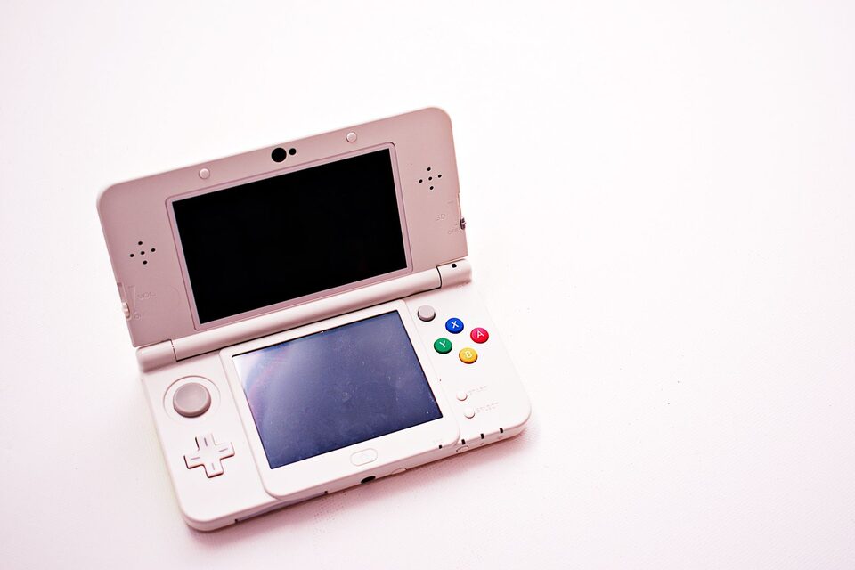 Een geopende roze draagbare console met twee uitgeschakelde schermen, illustratieve foto.