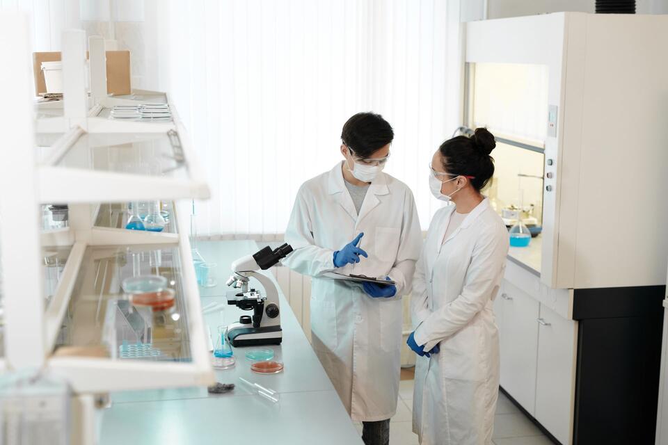 Two people talk beside a microscope in a laboratory, illustrative photo.