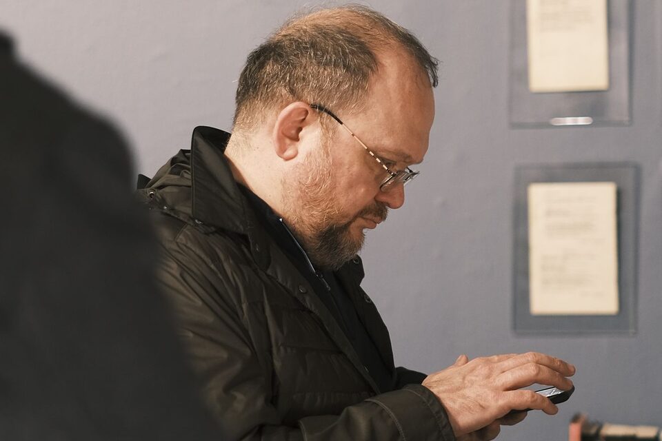 Un visiteur consulte son téléphone devant des vitrines de musée, photo d’illustration.