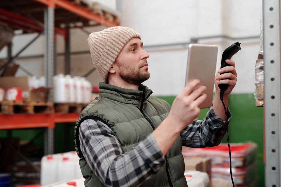 Un homme utilise un lecteur portatif et une tablette dans un entrepôt, photo d’illustration.