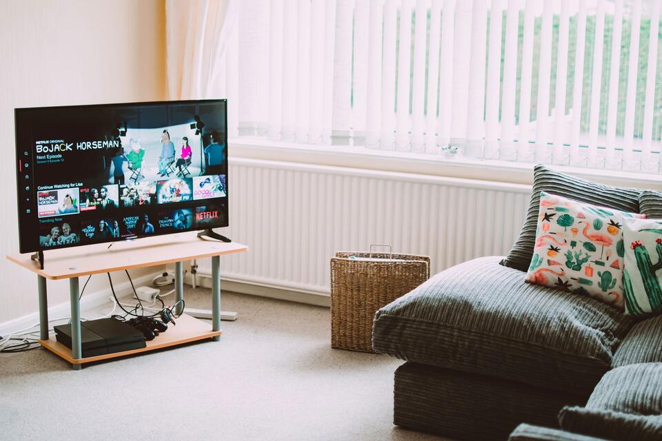 Une télévision allumée à côté d’un canapé dans un salon, photo d’illustration.